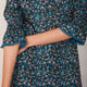 Close up showing the ruffle neckline and smocked tulip sleeve details of the Aimee dress.