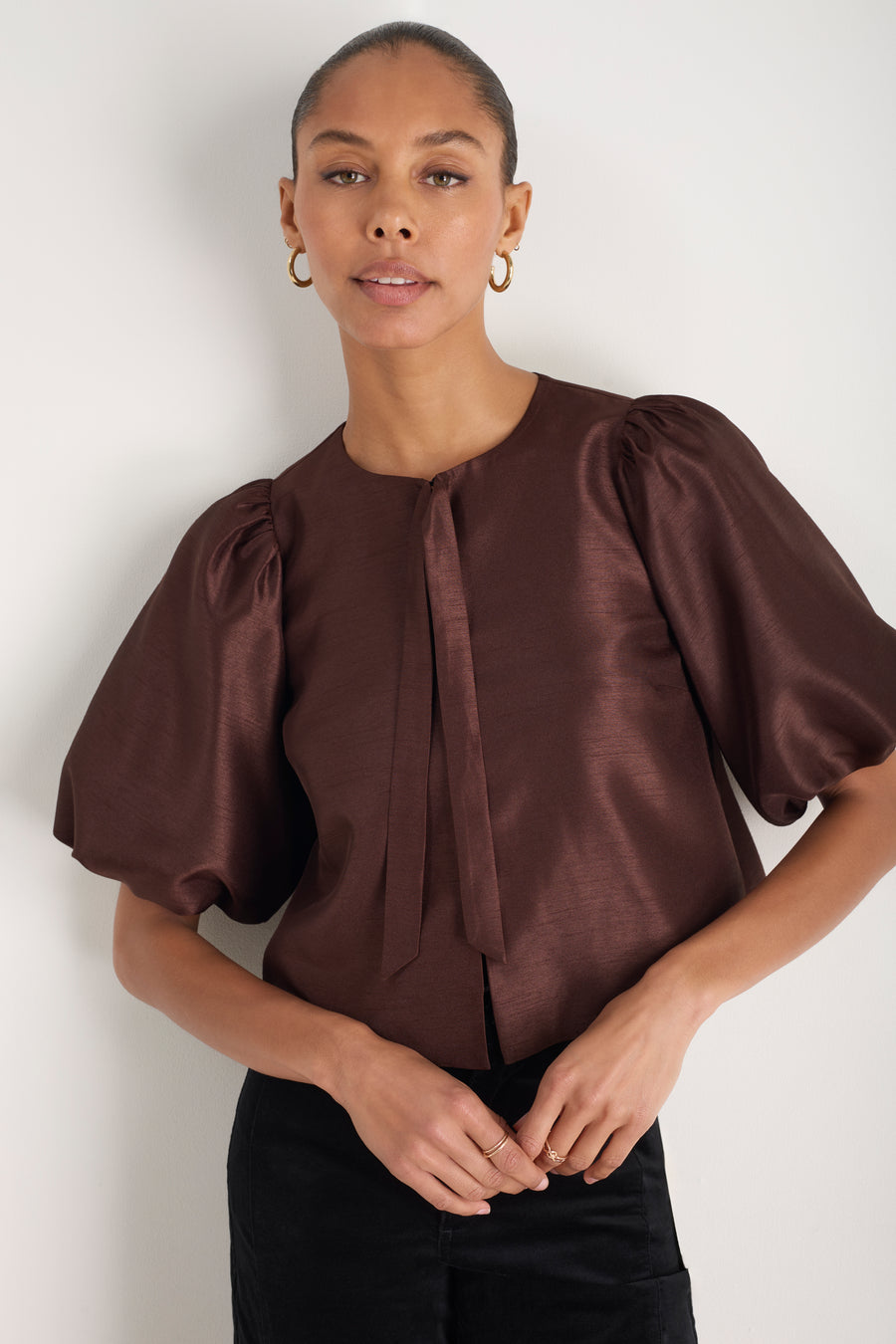 Model wearing a chocolate brown boxy top with balloon sleeves.