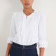 Model front view wearing white blouse with shirred cuffs.