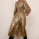 Woman wearing a metallic leopard print dress and gold shoes in a doorway.